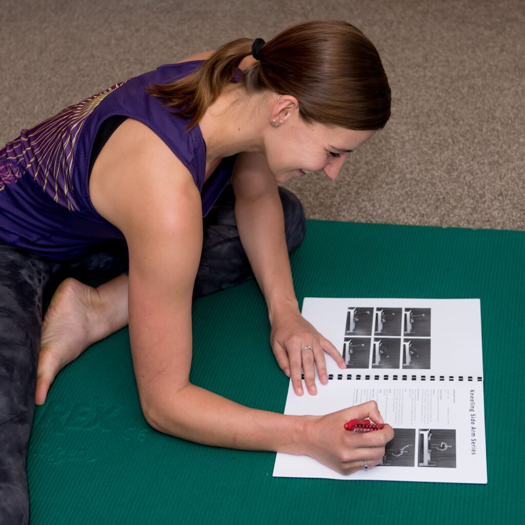 Hands-on teaching on the mat, with an anatomy chart alongside