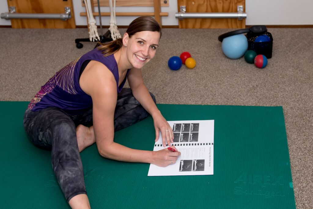 A Pilates teacher using an anatomy chart during a mat session