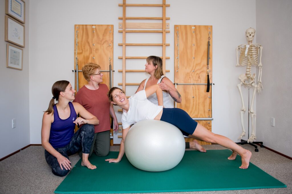 A client working on a large exercise ball with hands-on support