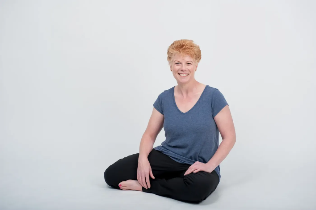Tania Huddart sitting cross-legged on the floor, smiling